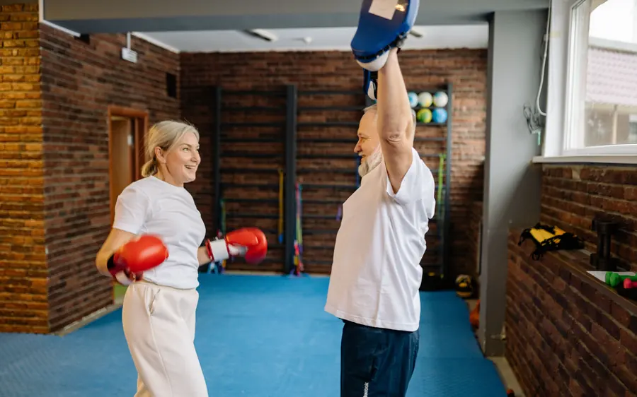 Mulher de cabelos grisalhos treinando boxe com o parceiro