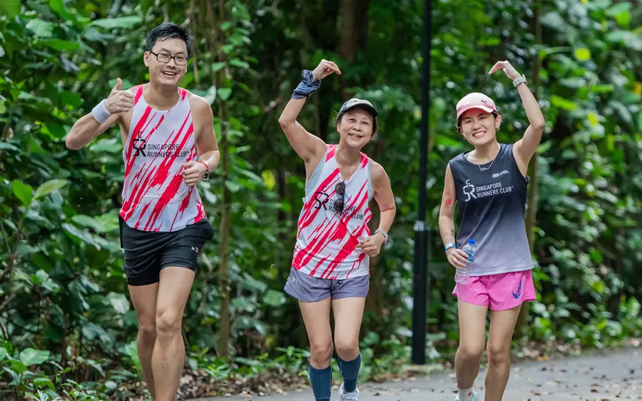 Três corredores sorrindo durante um treino em grupo no parque