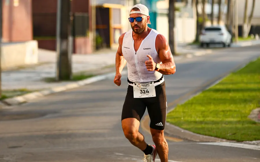 Atleta com número de peito correndo na rua durante uma prova