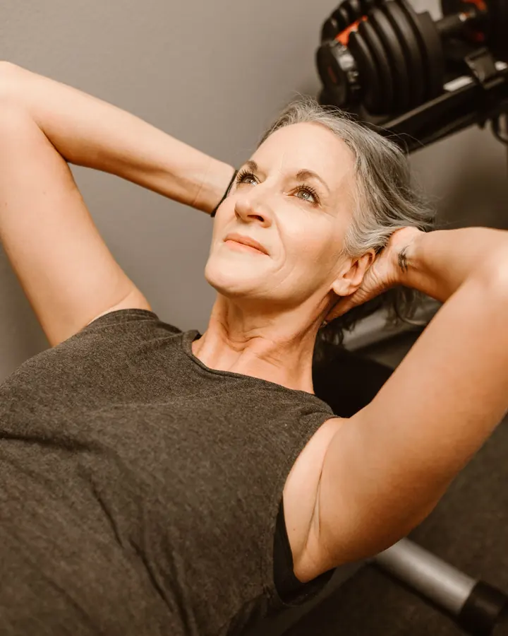 Mulher de cabelos grisalhos fazendo abdominal na academia