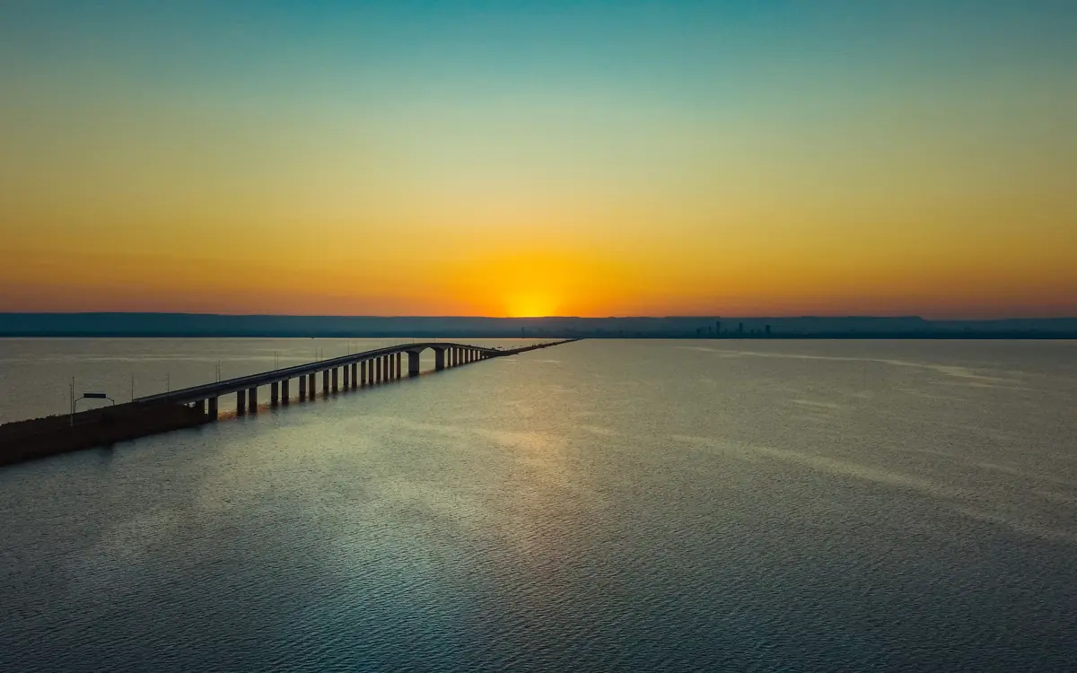 Ponte sobre o lago de Palmas ao pôr do sol, com a serra ao fundo