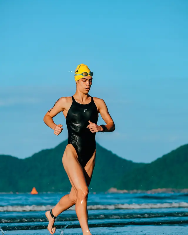 Triatleta saindo do mar e correndo na praia